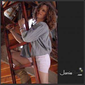 redhead transgender model janie black in white short skirt and cowboy boots on ladder to attic of barn hanging on